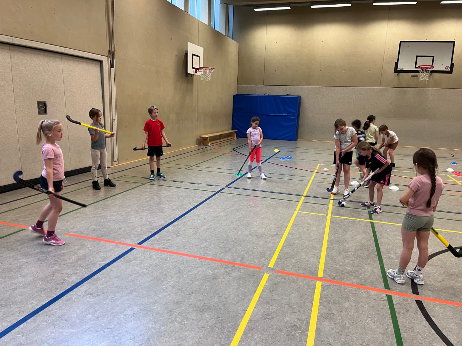 Schulkinder spielen Hockey in der Turnhalle