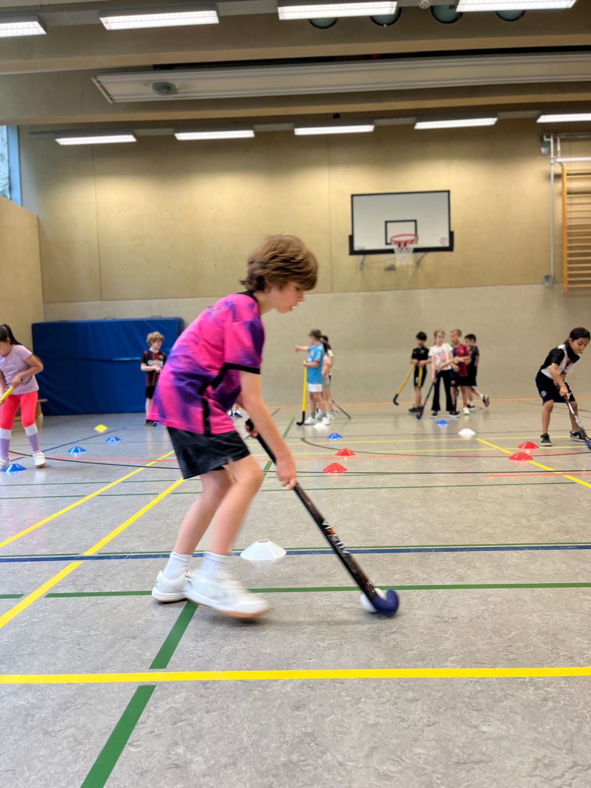 Ein Schulkind übt Hockey in der Turnhalle