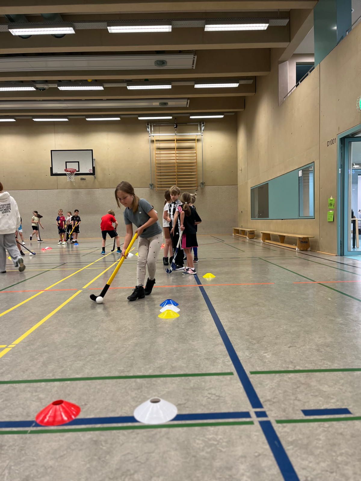 Ein Schulkind übt Hockey in der Turnhalle