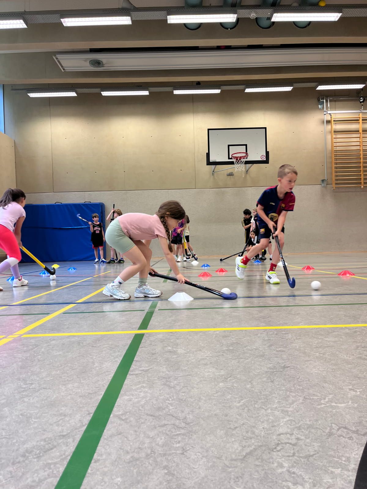 Zwei Schulkinder üben Hockey in der Turnhalle