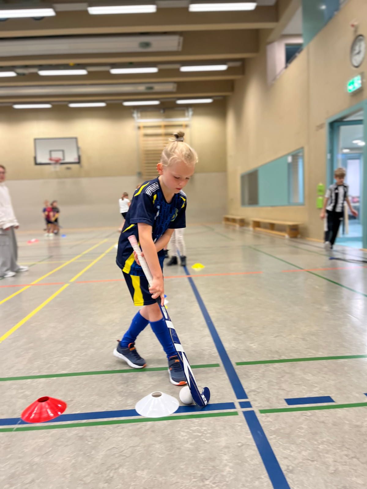 Ein Schulkind übt Hockey in der Turnhalle