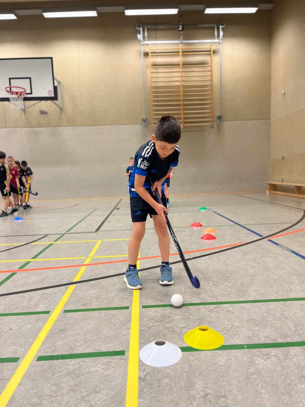 Ein Schulkind übt Hockey in der Turnhalle