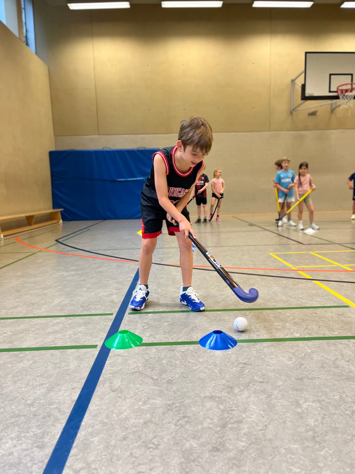 Ein Schulkind übt Hockey in der Turnhalle
