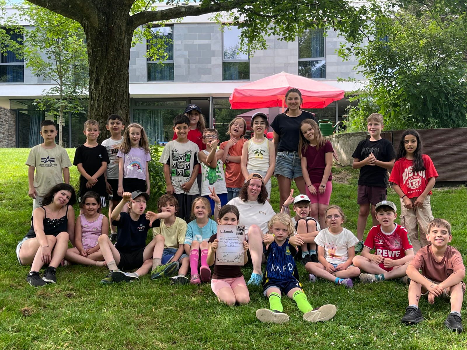 Gruppenbild von Schüler:innen mit ihrer Lehrerin an einem Baum