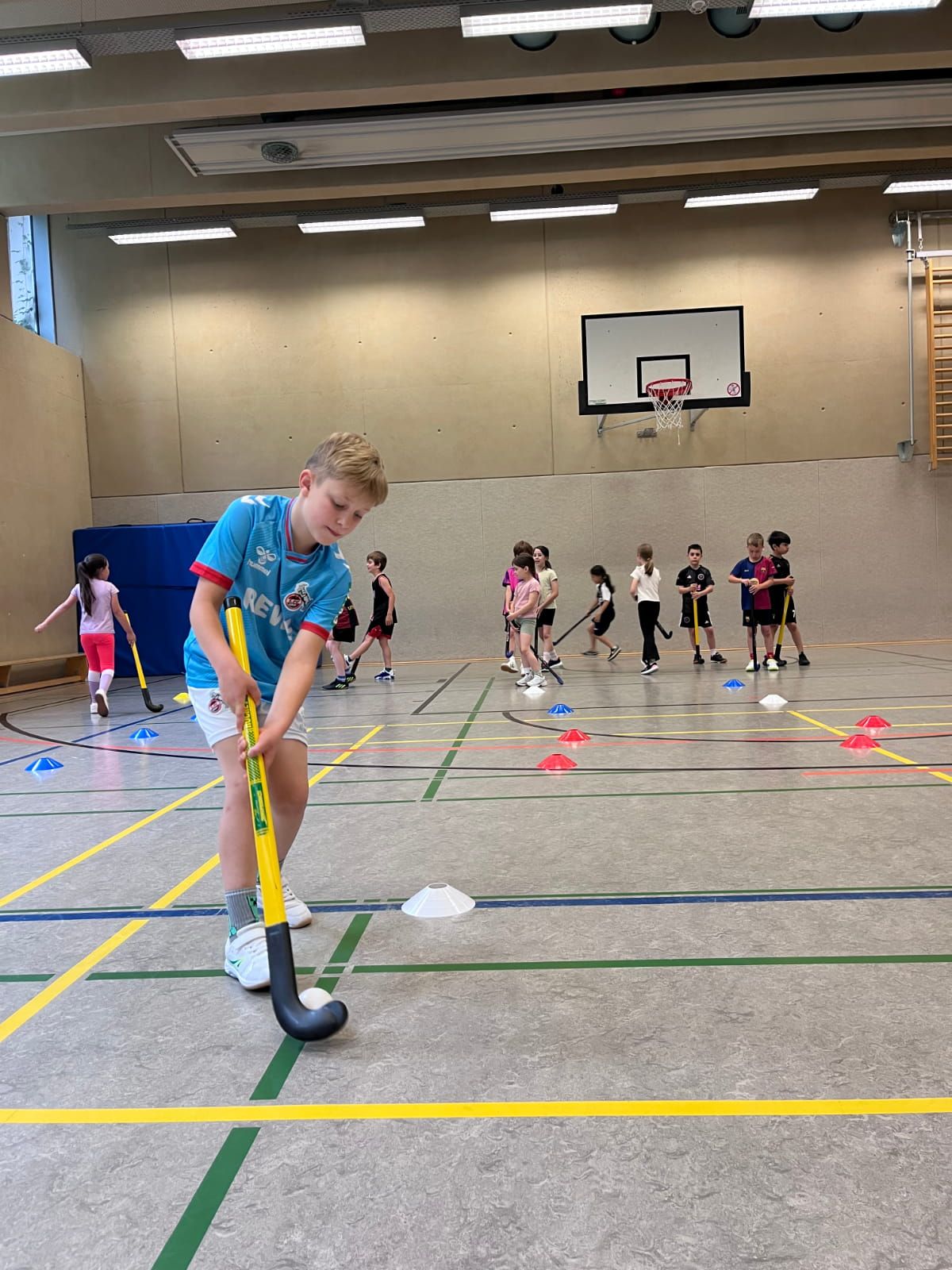 Ein Schulkind übt Hockey in der Turnhalle