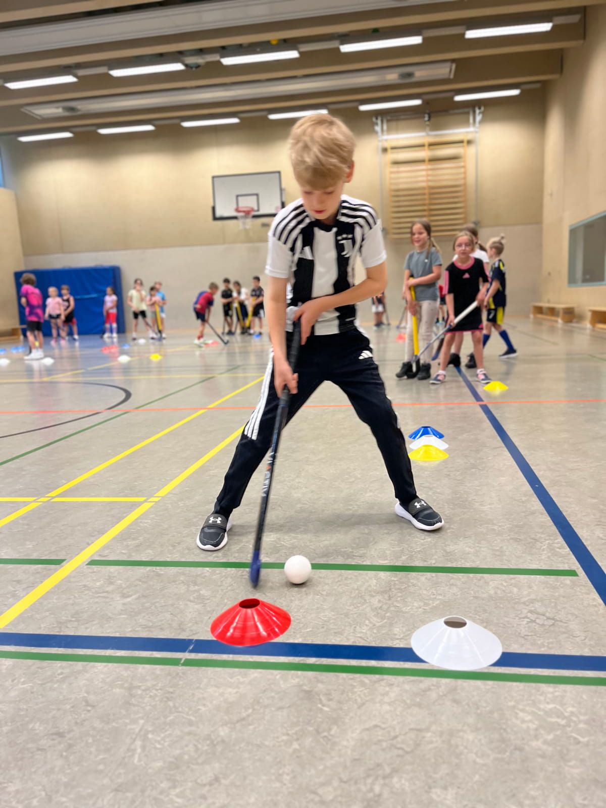 Ein Schulkind übt Hockey in der Turnhalle