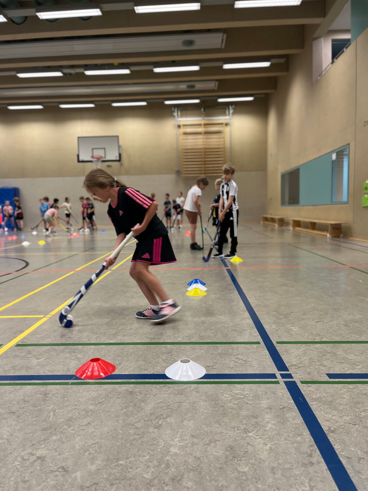 Ein Schulkind übt Hockey in der Turnhalle
