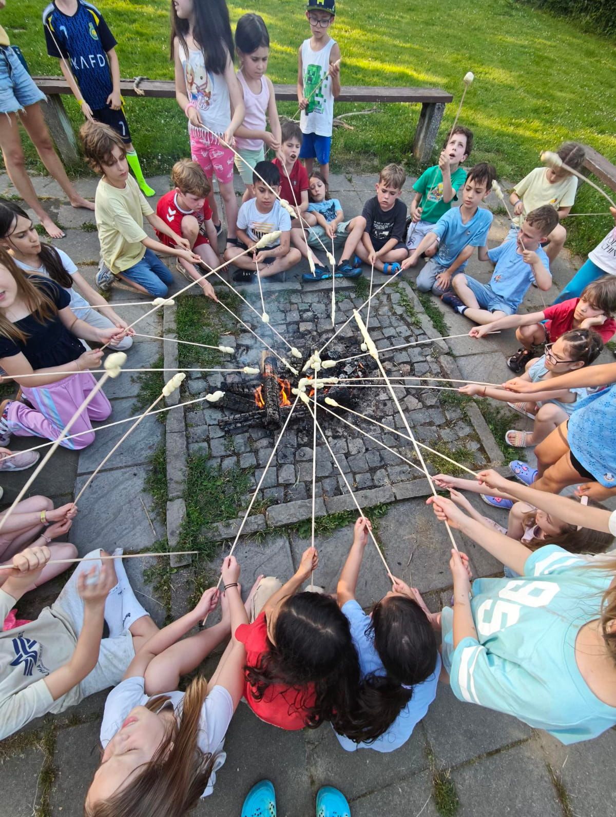Schüler:innen rösten Stockbrot über einem Lagerfeuer