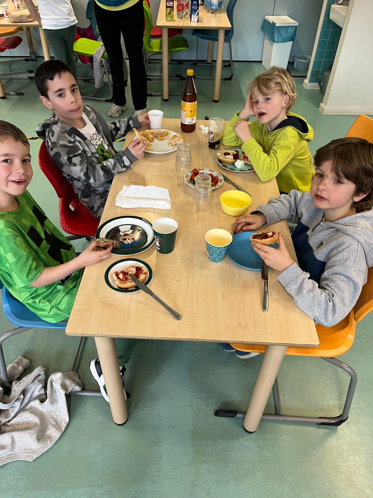 4 Kinder sitzen am Tisch und essen Frühstück