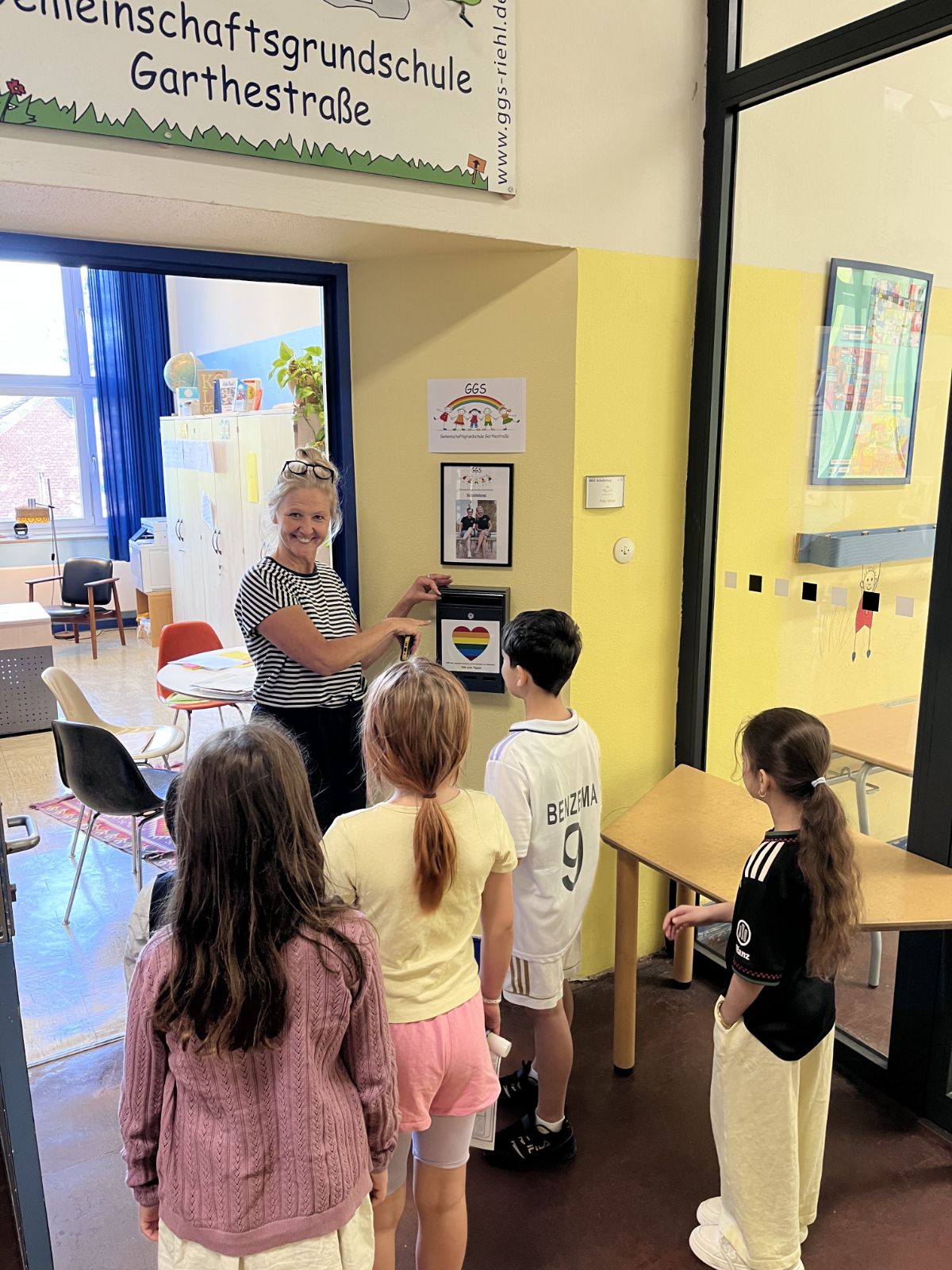 Vier Kinder stehen vor der Schulleiterin Frau Spiegel vor ihrem Raum