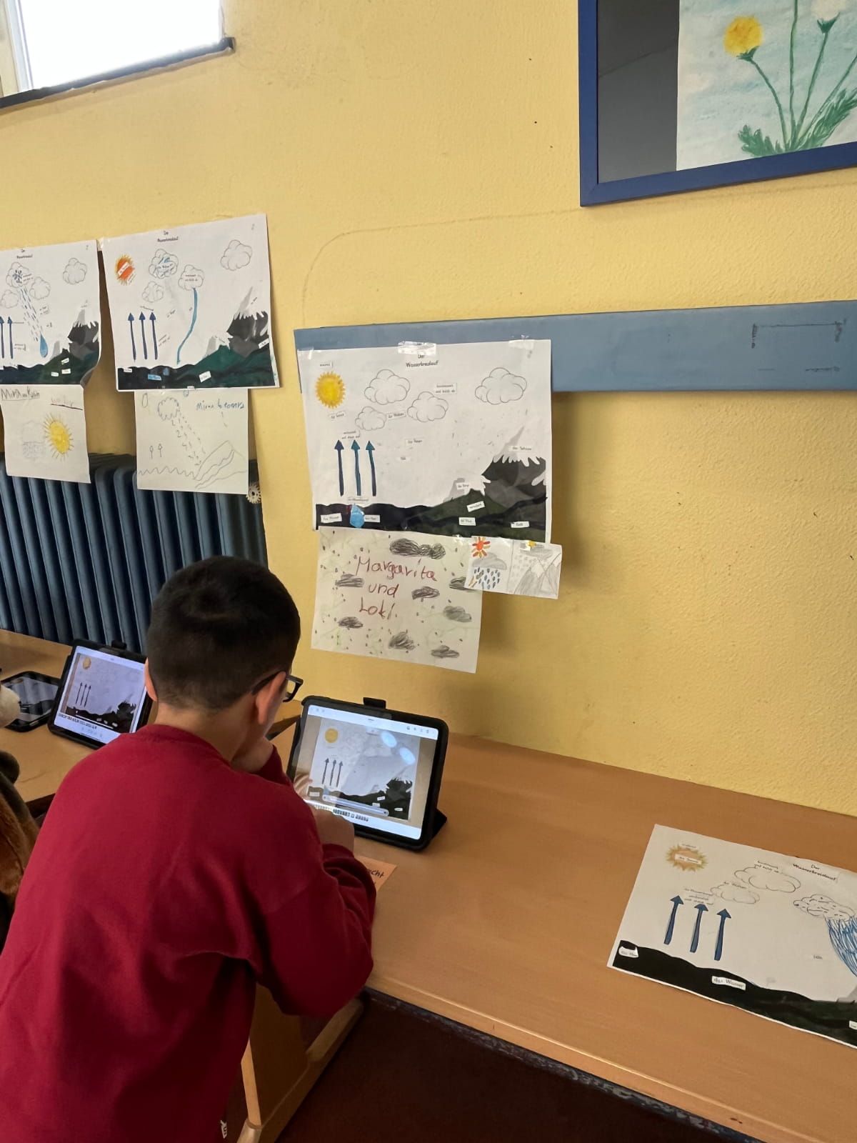 ein Kind sieht sich auf einem Tablett Informationen zum Wetter an