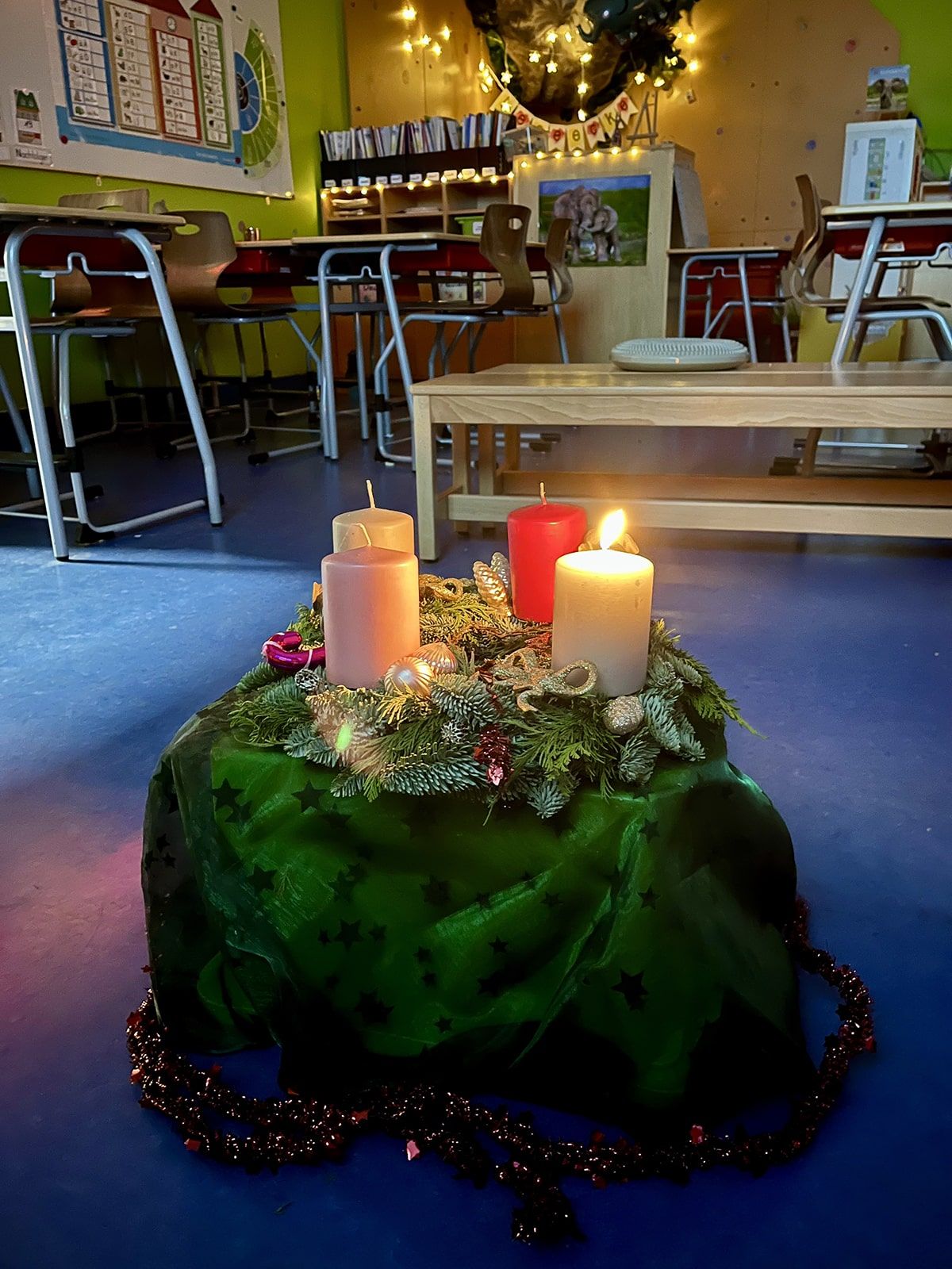 Adventskalender mit einer brennenden Kerze im Klassenraum