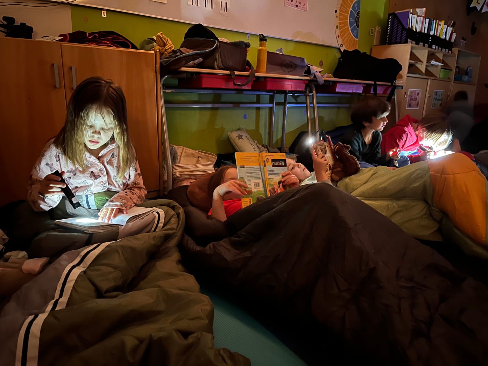 Kinder lesen zum Teil mit Taschenlampen in ihren Schlafsäcken