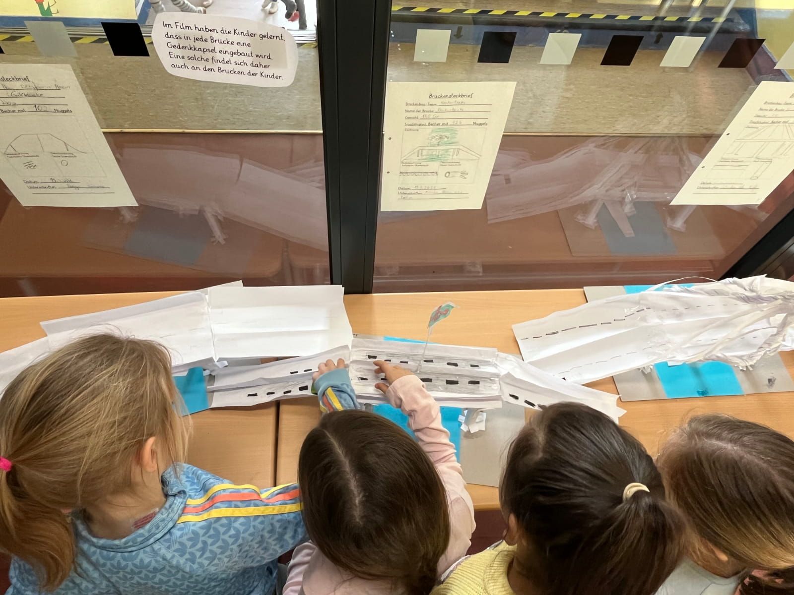 vier Kinder betrachten gebastelte Brücken