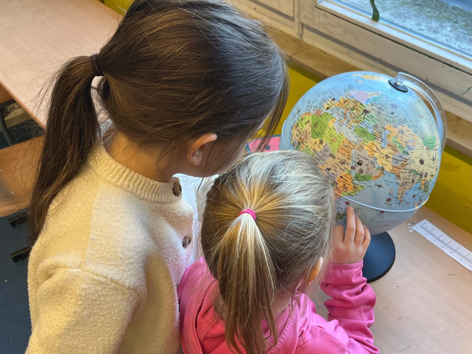 zwei Kinder betrachten einen Globus