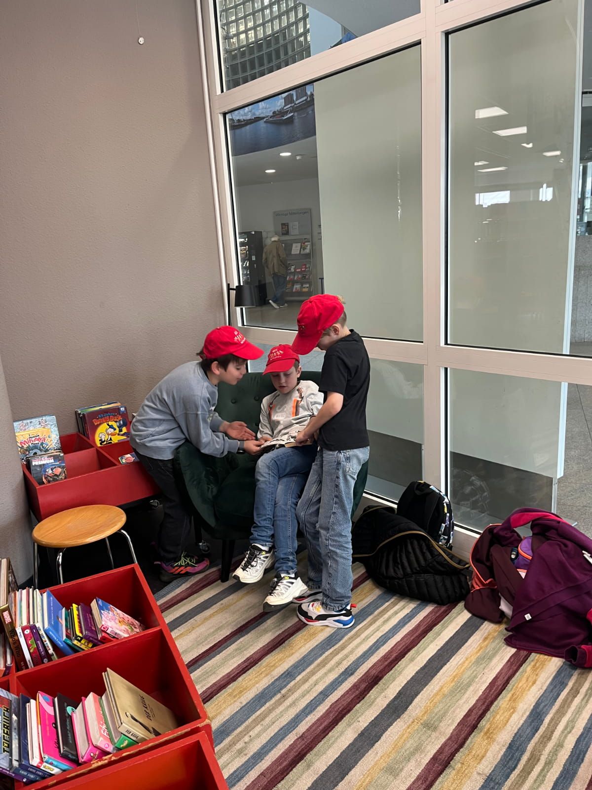 drei Kinder lesen ein Buch auf einem Sessel