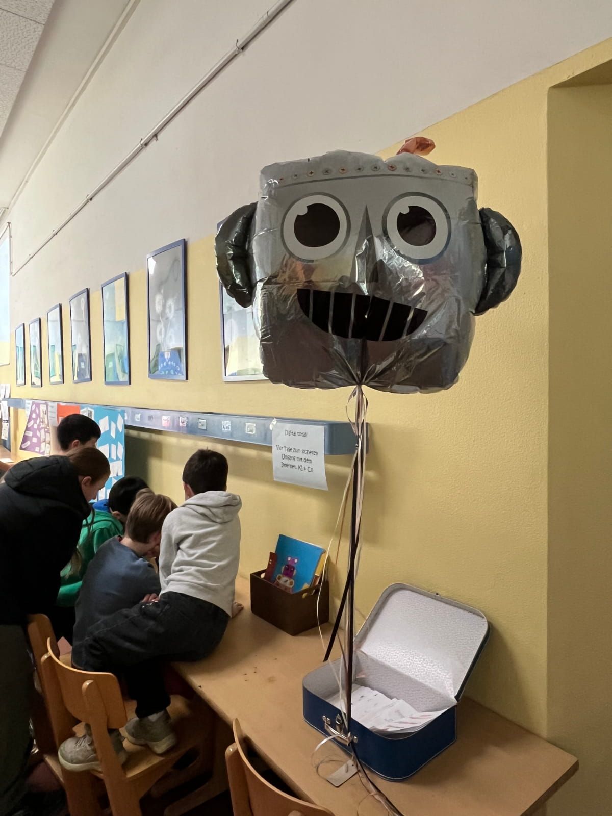 fünf Kinder sitzen im Flur und betrachten Arbeiten zu einem Forschungsthema