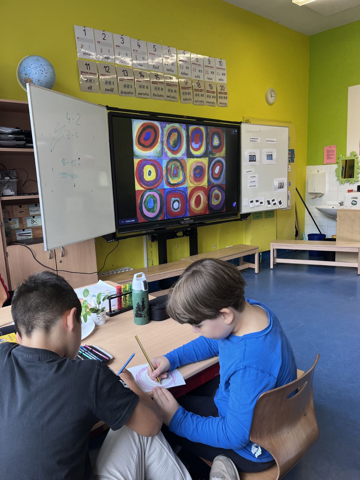 Zwei Kinder zeichnen zusammen an einem Tisch