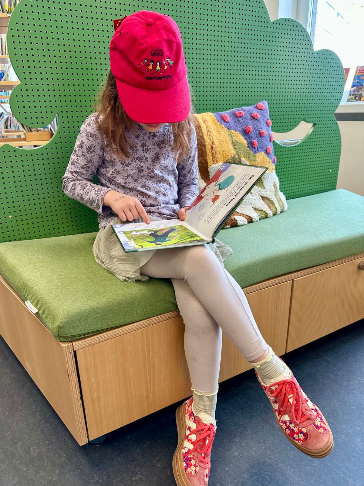 ein Kind liest ein Buch auf einer Bank