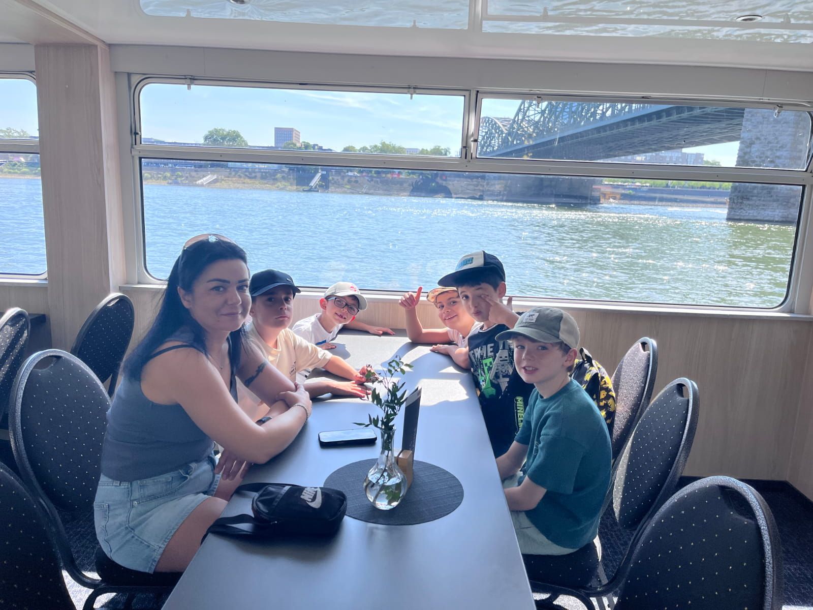 Fünf Schulkinder und eine Begleitung sitzen in einem Boot auf dem Rhein