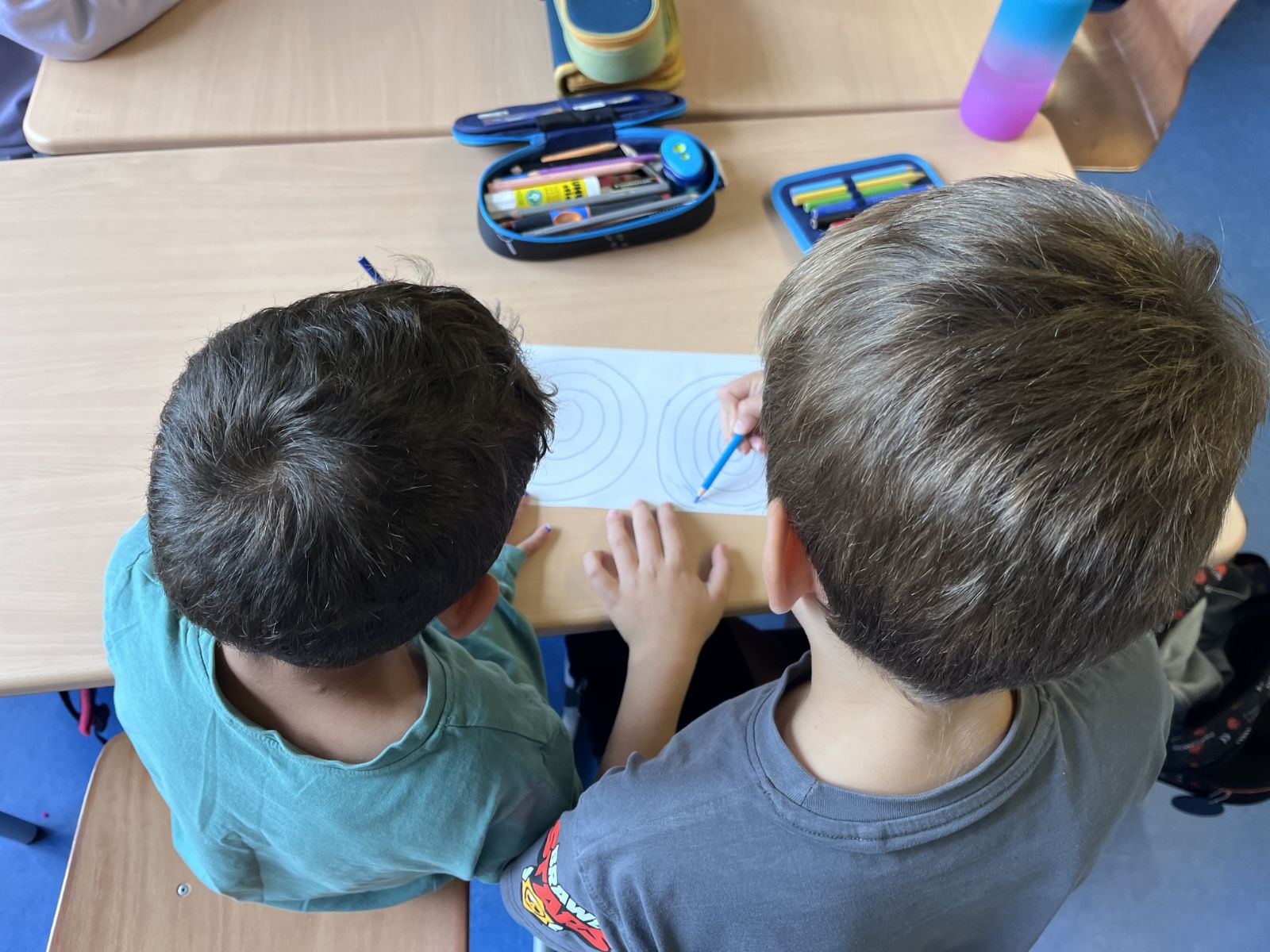 Zwei Kinder zeichnen zusammen an einem Tisch