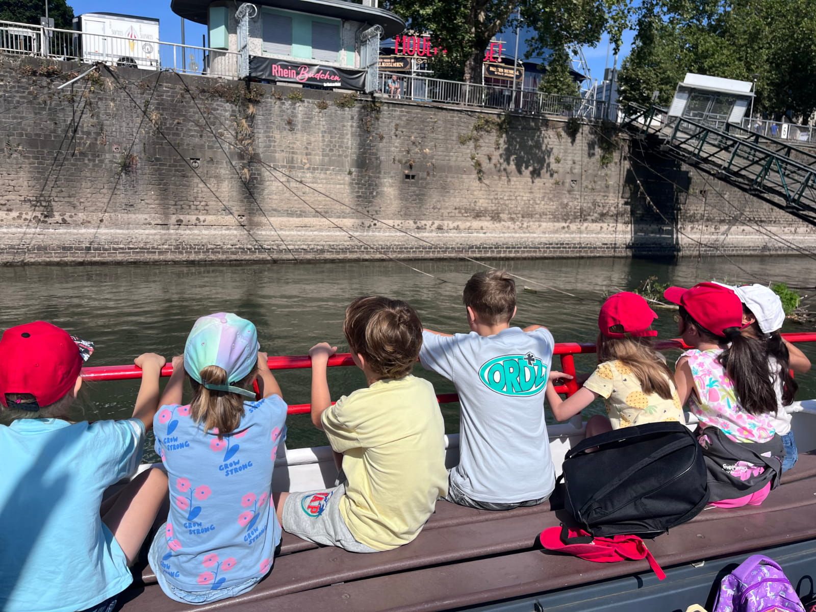 Sieben Kinder sitzen an Deck eines Bootes auf dem Rhein