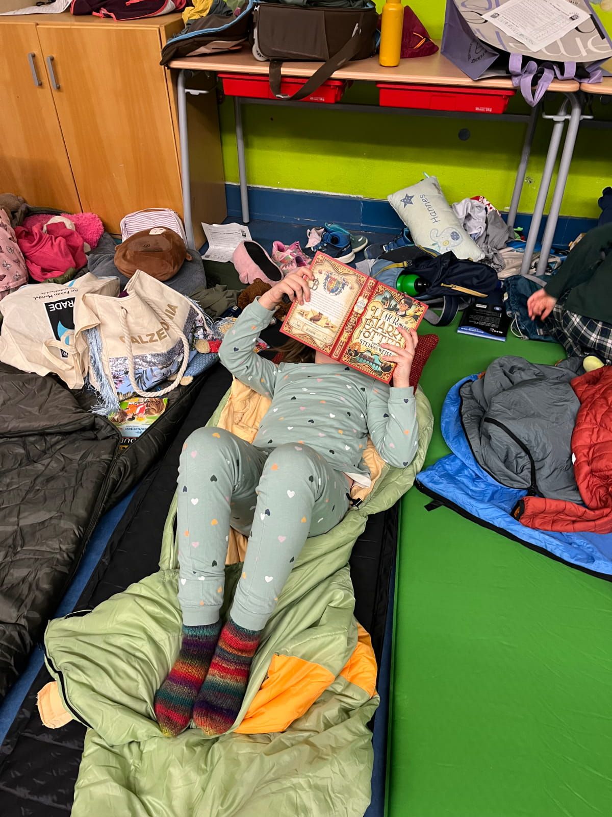 ein Kind liest auf seinem Schlafsack