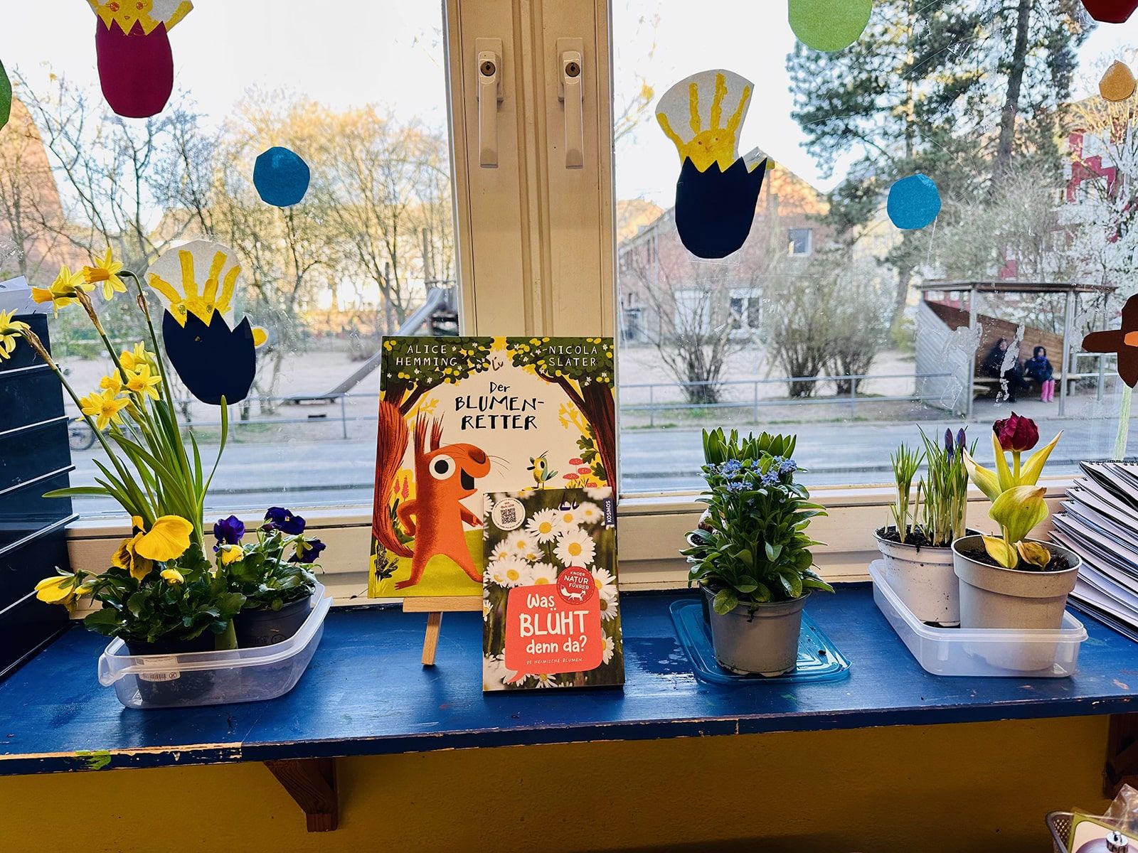 Das Buch "Blumenpeter" steht vor dem Fenster zusammen mit Blumen