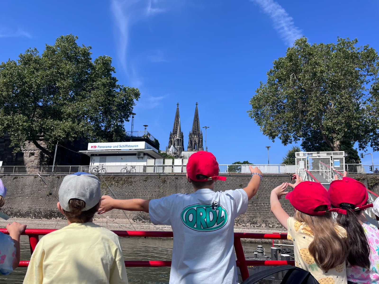 Vier Kinder sitzen an Deck eines Bootes auf dem Rhein