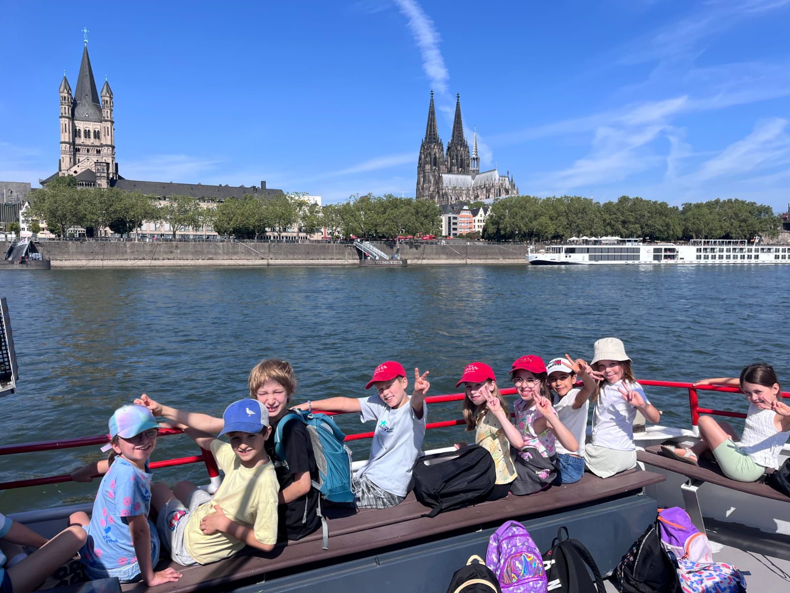 Schüler:innen sitzen an Deck eines Bootes auf dem Rhein