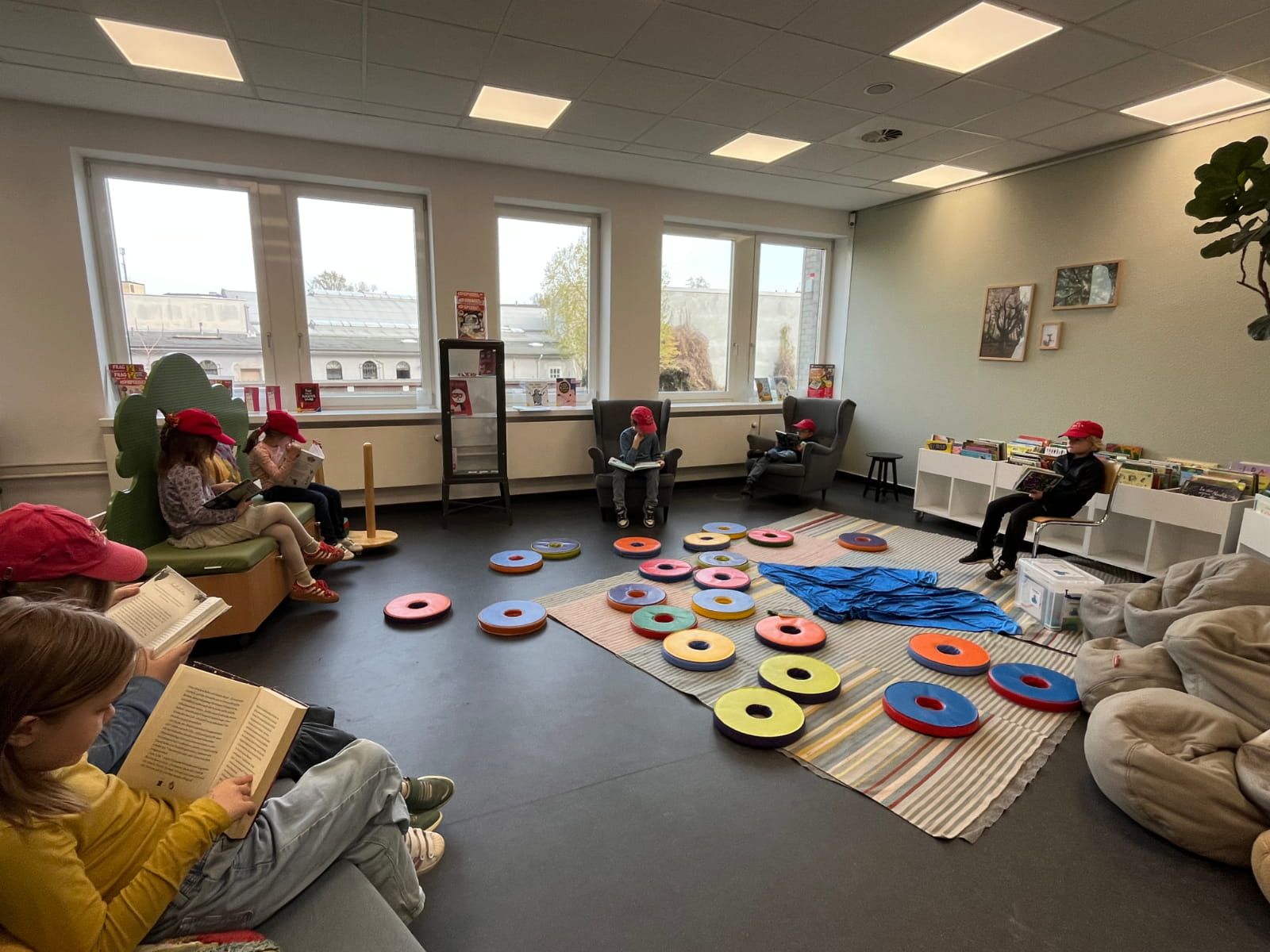 sieben Kinder lesen Bücher verteilt in einem Leseraum