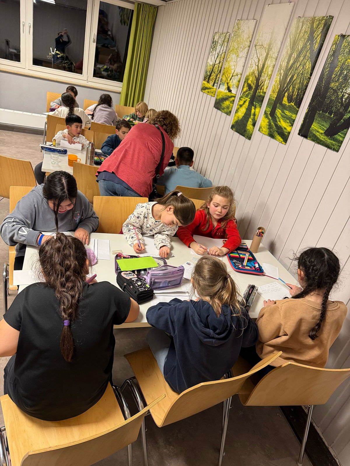 Kinder sitzen an Tischen und schreiben