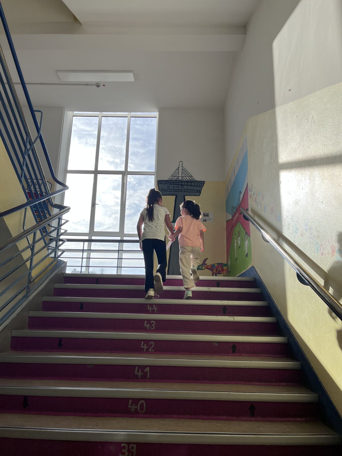 Zwei Kinder gehen zusammen eine Treppe herauf