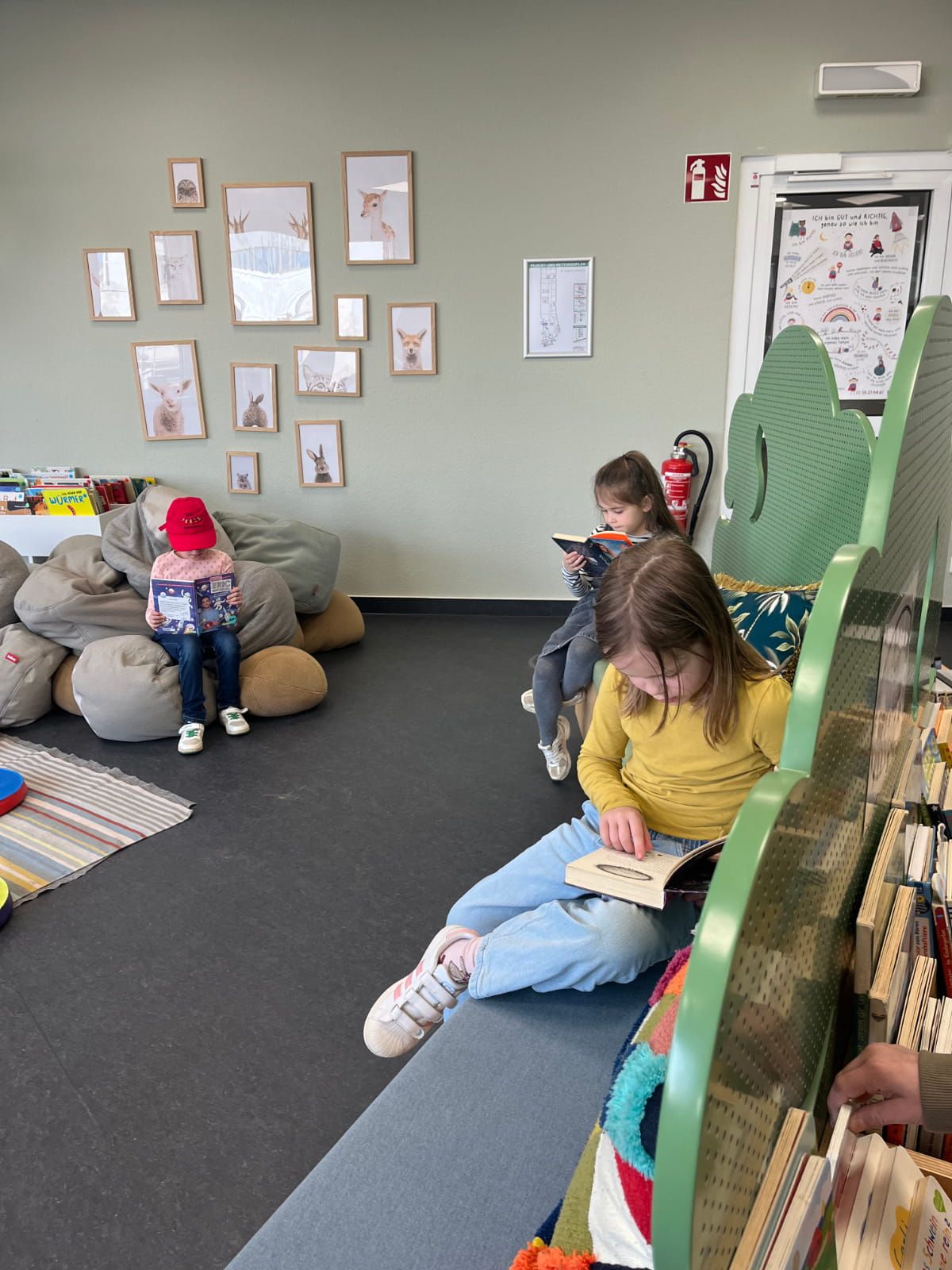 drei Kinder lesen Bücher verteilt in einem Leseraum