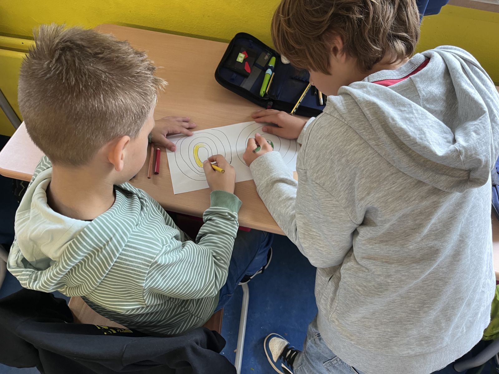 Zwei Kinder zeichnen zusammen an einem Tisch