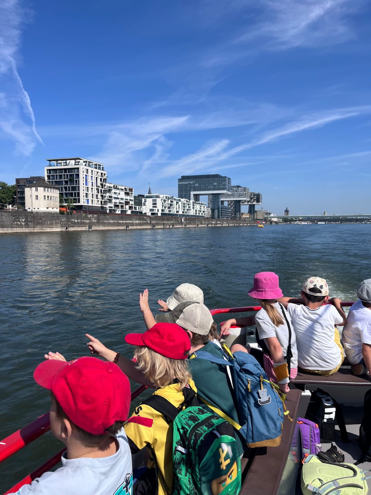 Schulkinder sitzen an Deck eines Bootes auf dem Rhein